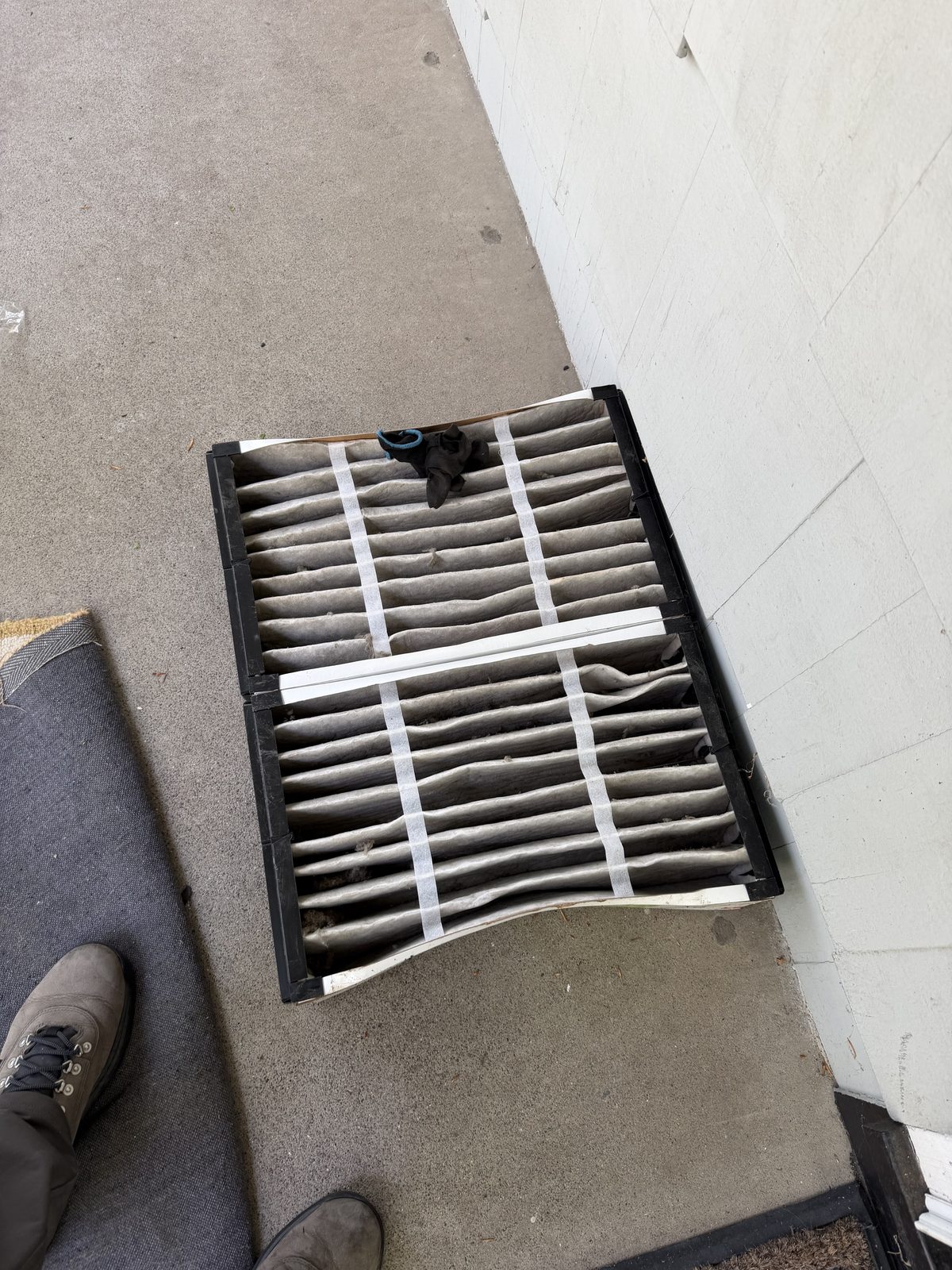 A pleated air filter gone gray with dust, just pulled from the system