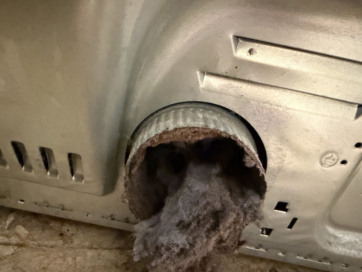 Lint bursting out of the exhaust outlet on the back of a dryer
